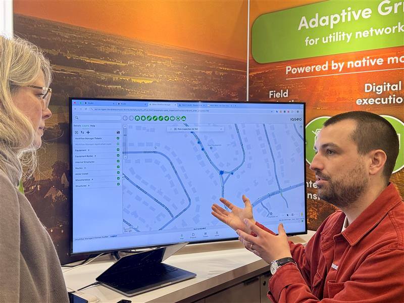DISTRIBUTECH 2025のブースをクローズアップした写真。画面にはIQGeoソフトウェアが表示されている。